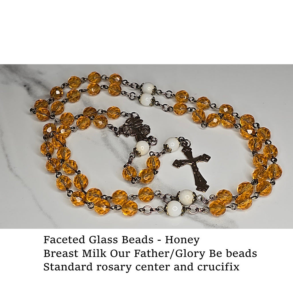 Rosary with honey-colored faceted glass Hail Mary beads and crucifix on a marble surface