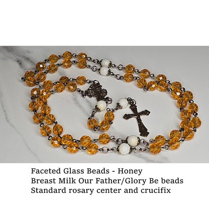 Rosary with honey-colored faceted glass Hail Mary beads and crucifix on a marble surface