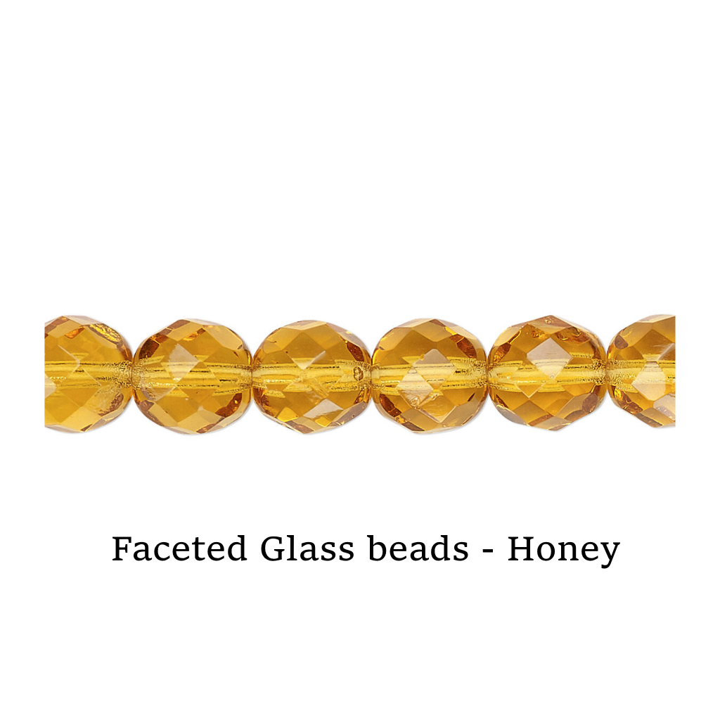 Faceted glass beads in honey color on a white surface