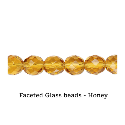 Faceted glass beads in honey color on a white surface