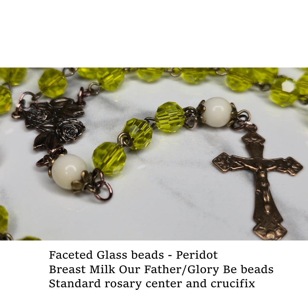 Rosary with peridot-colored faceted glass Hail Mary beads and crucifix on a marble surface