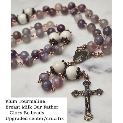 Rosary with plum tourmaline and breast milk beads on a marble surface