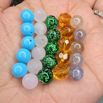 Turquoise, Rose Quartz, Green Lava Rock, Faceted Glass Honey, and Plum Tourmaline beads arranged in a hand